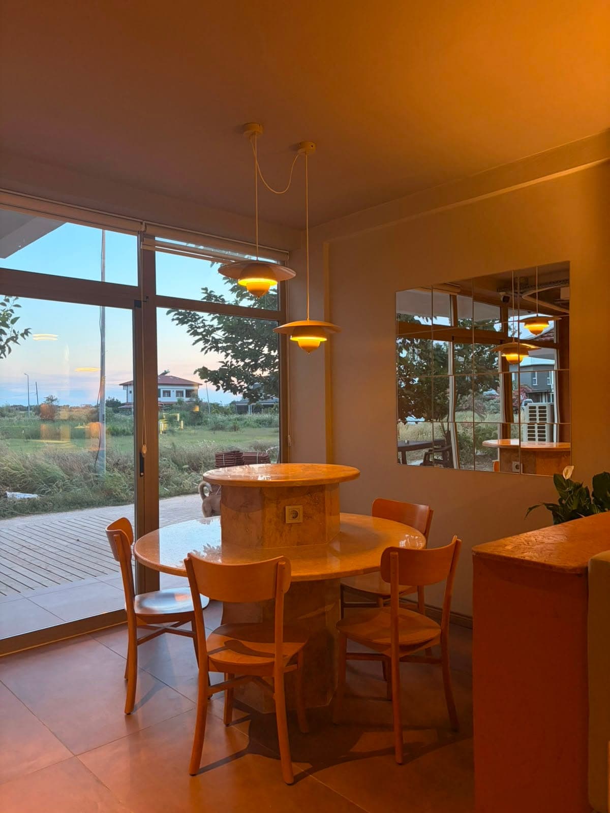 Cam cepheye bakan köşe masa, sarkıt lambalar ve gün batımı ışığı